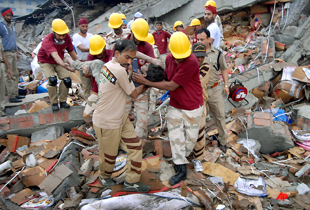 Rescue workers remove a worker from the debris of a collapsed factory in Jalandhar, India, Monday, April 16, 2012. The building, housing a blanket manufacturing factory, collapsed after a blast in the factory's boiler. (AP Photo/ Shammi Mehra)