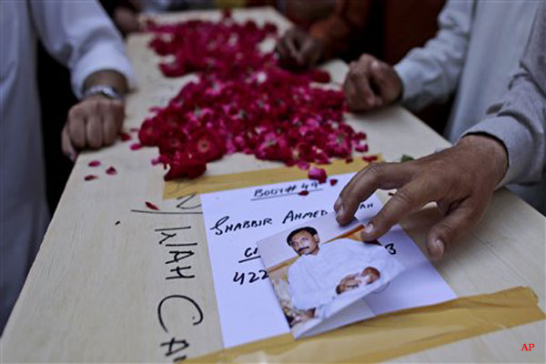 A Pakistani relative of Shabbir Ahmed, who lost his life in Friday's crash of a Bhoja Air Boeing 737 passenger plane, places his picture on his coffin, after displaying it to members of the media, outside a hospital in Islamabad, Pakistan, Saturday, April 21, 2012. Pakistan blocked the head of the airline whose jet crashed near the capital from leaving the country as it began an investigation Saturday into the country's second major air disaster in less then two years. (AP Photo/Muhammed Muheisen)