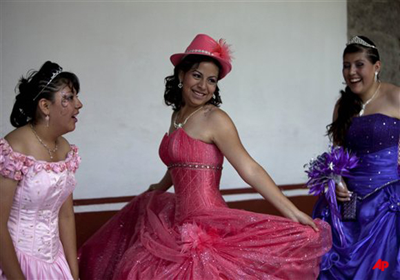 Cecilia, center, 15 year old girl plays with her dresse before a mass Quinceanera birthday celebration in Mexico City, Saturday, April 28, 2012. The Quinceanera marks the transition from childhood to adulthood and is common in Mexico and other Spanish speaking countries. (AP Photo/Dieu Nalio Chery)