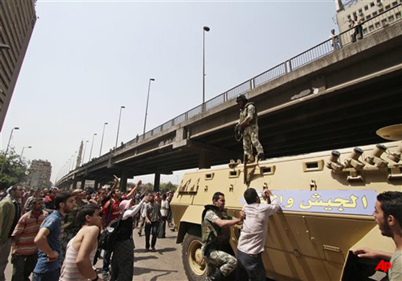 An Egyptian solider pushes a man trying to rip a banner on a tank in Arabic that reads, the military and the people, one hand , outside the Defense Ministry in Cairo, Egypt, Wednesday, May 2, 2012. Suspected supporters of Egypt's military rulers attacked predominantly Islamist anti government protesters outside the Defense Ministry in Cairo Wednesday, setting off clashes that left more than ten people dead as political tensions rise three weeks before crucial presidential elections. (AP Photo)