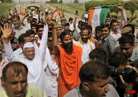 India's anti corruption crusader Anna Hazare, left, and Indian yoga guru Baba Ramdev hold hands as they greet their supporters after paying their tributes at Rajgaht, Mahatma Gandhi memorial, in New Delhi, India, Sunday, June 3, 2012. India's iconic anti corruption campaigners Hazare and Ramdev are holding a daylong fast near Indian parliament house to press the government to act against widespread graft and bring back hundreds of billions of dollars stashed overseas. (AP Photo/Manish Swarup)