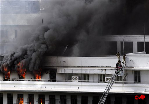 Rescue workers evacuate people as smoke engulfs the Maharashtra state government building in Mumbai, India, Thursday, June 21, 2012. Hundreds of employees were evacuated Thursday from the seven story government building as more than two dozen fire engines battled the major fire that raged for more than three hours in India's financial and entertainment capital. (AP Photo/Rajanish Kakade)