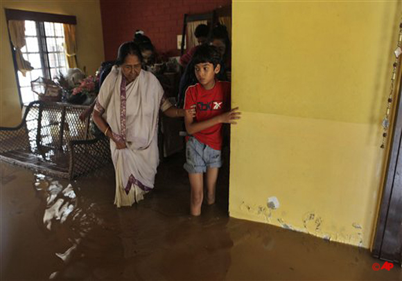 People prepare to leave their house following an inundation of flood water in Guwahati, India, Tuesday, June 26, 2012. Flooding in the north eastern Assam state on Tuesday turned grim with most of the rivers breaching embankments and inundating new areas. Road links have been cut in many places and at least ten people have died according to local news reports. (AP Photo/Anupam Nath)