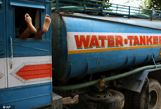 The driver of a government tanker delivering drinking water sleeps with his feet out the window in New Delhi. Many areas of the capital are facing acute water shortage, a repeated annual phenomenon during summer when taps go dry as demand rises. (AP Photo/Kevin Frayer)