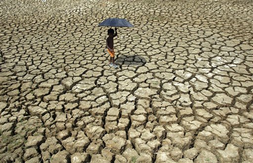 A village boy uses an umbrella to protect himself from the heat as he walks on a dried water bed near Basudevpur village, about 140 kilometers (88 miles) from the eastern Indian city of Bhubaneshwar, Saturday, April 17, 2010. Places across north India have been experiencing a heat wave condition, with temperature in the capital New Delhi crossing 42.9 degrees Celsius (109.2 Fahrenheit), according to news reports. (AP Photo/Biswaranjan Rout)