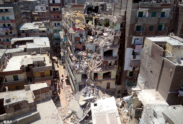 Rescue workers look for survivors buried under debris of damaged buildings following the collapse of an 11 story building under construction onto three adjacent buildings that killed at least 10 people in the Gomrouk neighborhood of Alexandria, Egypt, July 15, 2012. (AP Photo)