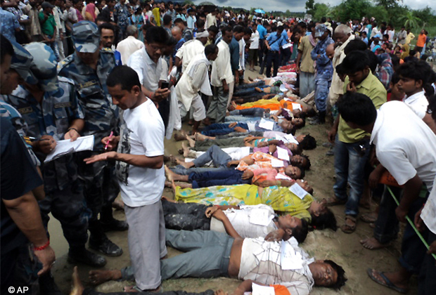 People stand around the bodies of victims after an overcrowded bus carrying Hindu pilgrims skidded off a slippery highway near Raninagar about 160 kilometers (100 miles) southwest of Katmandu, Nepal, Sunday, July 15, 2012. Rescuers recovered 90 bodies, officials said. (AP Photo)