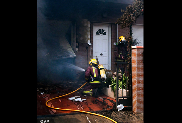 Firefighter extinguish a fire in a house as wild fires get close to the house in La Jonquera, near the border with France, Spain, Sunday, July 22, 2012. The regional officials said wildfires have burned almost 7,000 hectares (17.297 acres) of forest. (AP Photo/Josep Ribas)