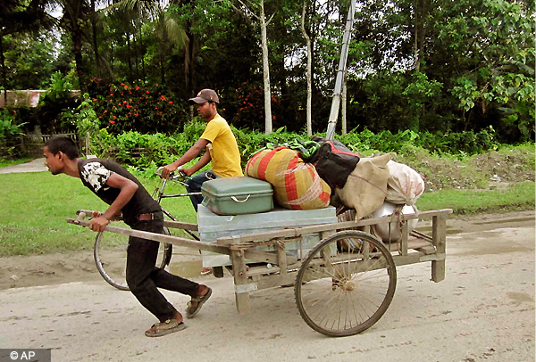 An Indian man carries his belongings to a safe place in Kokrajhar, Assam. Tens of thousands of villagers have fled their homes in fear of rioting that has killed at least 38 people in recent days in Assam. (AP Photo)