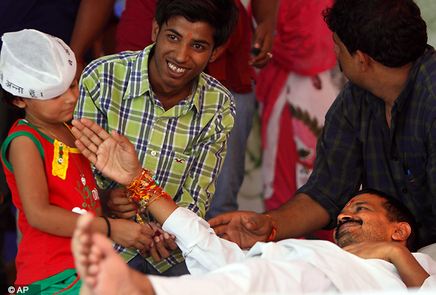 A young supporter of India's anti corruption activist Anna Hazare ties a rakhi, or a sacred thread, on the wrist of key aide and rights activist Arvind Kejriwal to mark the occasion of Raksha Bandhan that celebrates the relationship between brothers and sisters during a protest at Jantar Mantar in New Delhi, India, Thursday, Aug. 2, 2012. (AP Photo)