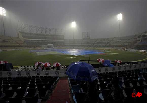 Spectators hold umbrellas as rain stops play on the third day of the first cricket test match between New Zealand and India in Hyderabad, India, Saturday, Aug. 25, 2012. (AP Photo/Mahesh Kumar A.)