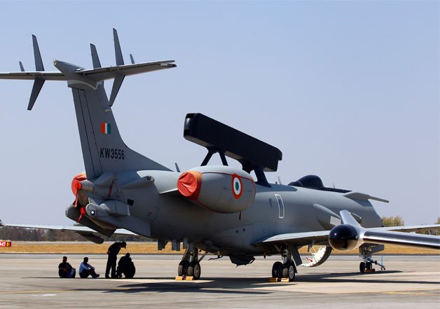 Engineers and support staff sit in the shade of an Embraer EMB 145I aircraft fitted with the country's first indigenous airborne radar system called the Airborne Early Warning and Control System, during rehearsals for the Aero India 2015 at Yelahanka air base in Bangalore.