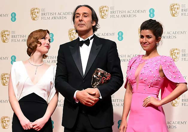 Holliday Grainger, left and Nimrat Kaur, right, pose with Alexandre Desplat, winner of Best Original Music for The Grand Budapest Hotel, in the winners room, during the British Academy Film and Television Awards 2015, at the Royal Opera House, in London,