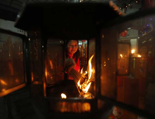 A woman burns joss sticks on the eve of the Chinese Lunar New Year at the Hea Tek Tunk Chinese Temple in Bangkok, Thailand.