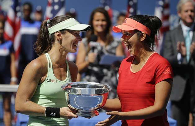 Martina Hingis, of Switzerland, left, and Sania Mirza, of India, celebrate with the championship trophy after defeating Casey Dellacqua, of Australia, and Yaroslava Shvedova, of Kazakhstan, in the women's doubles championship match of the U.S. Open tennis tournament in New York.